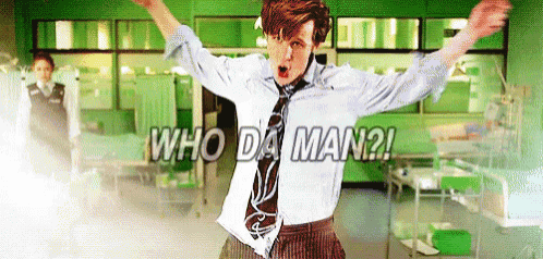 a man in a suit and tie is standing in a hospital room with his arms in the air and says who da man