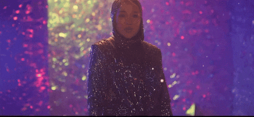 a woman wearing a hijab and a sequined outfit is dancing with her arms outstretched