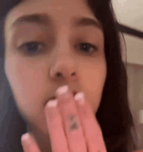 a close up of a woman 's face with her hands on her mouth .