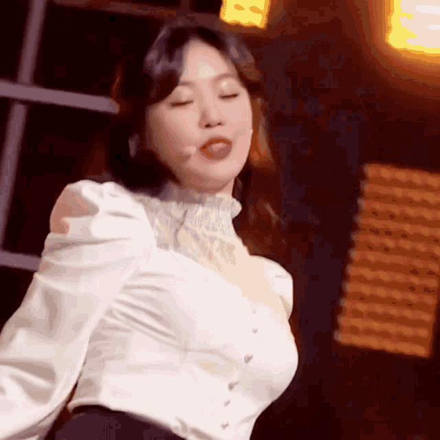a woman in a white shirt is dancing on a stage .
