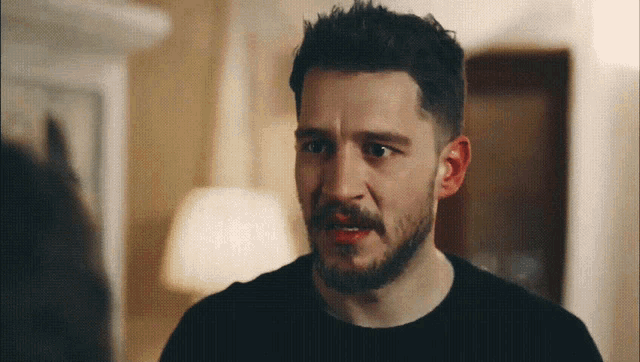 a man with a beard wearing a black shirt is making a funny face