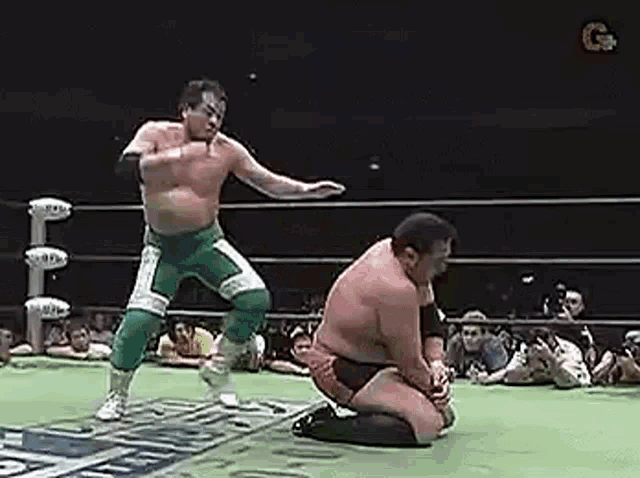 two men are wrestling in a ring with a crowd watching .