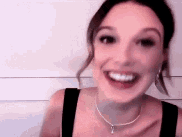 a close up of a woman wearing a necklace and earrings smiling .
