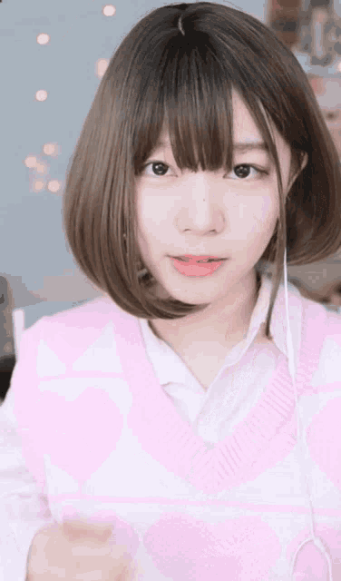 a girl with short hair is wearing a pink vest and headphones