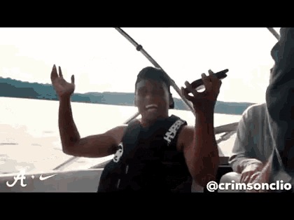 a man in a life jacket is sitting on a boat holding a microphone