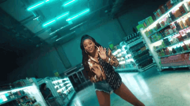 a woman is dancing in a grocery store aisle with a sign that says ' a ' on it