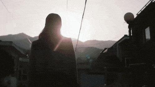 a woman is walking down a street with the sun shining through her hair .