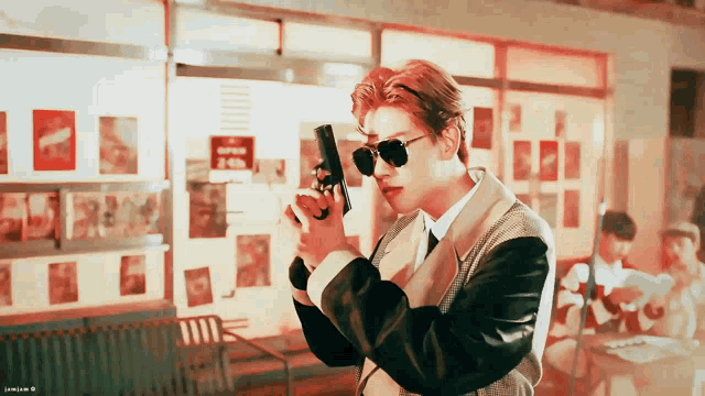 a man wearing sunglasses is holding a gun in his hand
