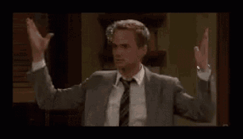 a man in a suit and tie is standing in a room with his arms in the air .