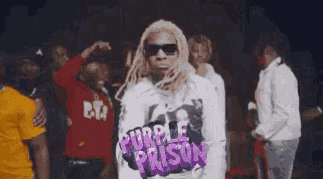 a man in a purple prison shirt is standing in front of a crowd of people