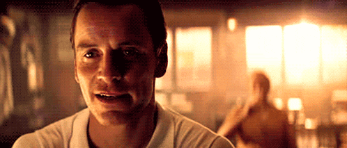 a man in a white shirt is looking at the camera in a dark room