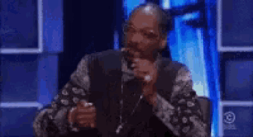 a man with a beard is sitting in front of a microphone in a chair .