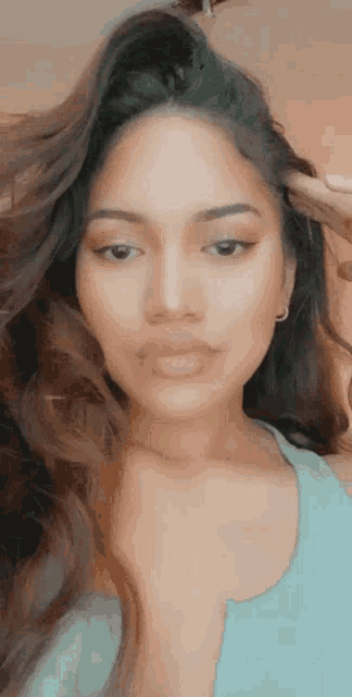 a close up of a woman 's face with long hair and a blue tank top .