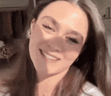 a close up of a woman 's face with long hair smiling .