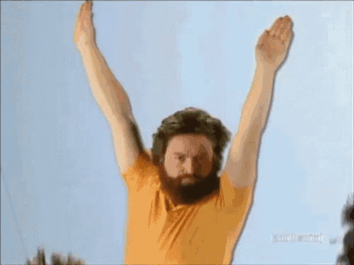 a man with a beard and a yellow shirt is raising his arms in the air ..
