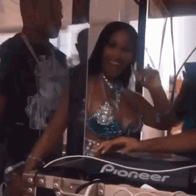 a woman in a bikini is standing in front of a pioneer dj booth