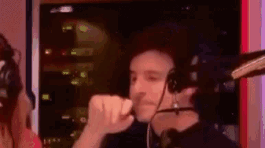 a man wearing headphones and a microphone is sitting in front of a microphone .
