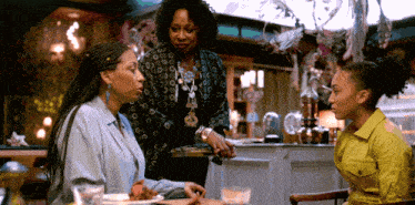 three women are sitting at a table in a room