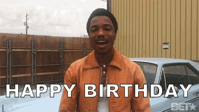 a man is standing in front of a car and says happy birthday