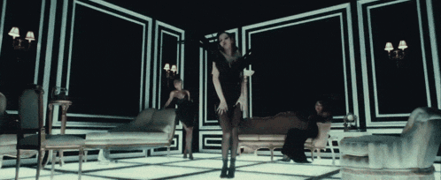 a woman in a black dress is dancing in a room with a couch