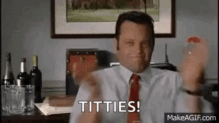 a man in a suit and tie is sitting at a desk holding a bottle of wine and saying titties .
