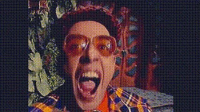 a man wearing sunglasses is making a funny face with his tongue out .