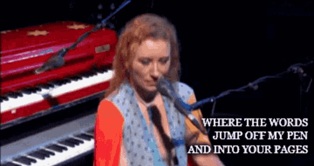 a woman singing into a microphone while playing a red piano