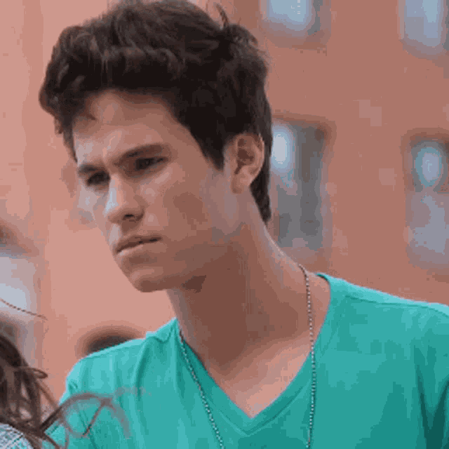 a young man wearing a green t-shirt and a necklace