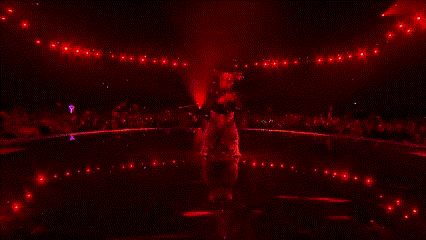 a group of people dancing on a stage in front of a large red moon