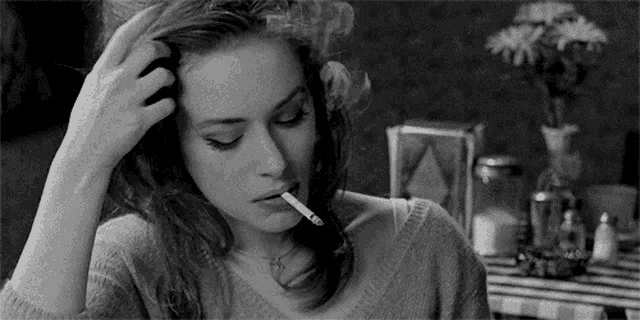 a young woman is smoking a cigarette in a black and white photo .
