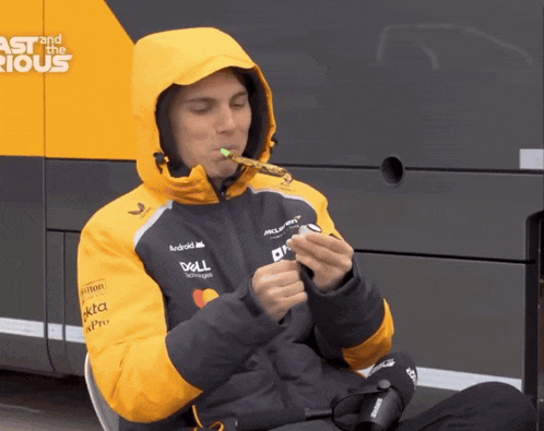 a man wearing a jacket that says dell on it is smoking a cigarette