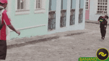 a man with a backpack is walking down a street next to a sign that says bananano