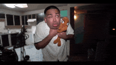 a man in a white shirt is holding a stuffed animal in his mouth