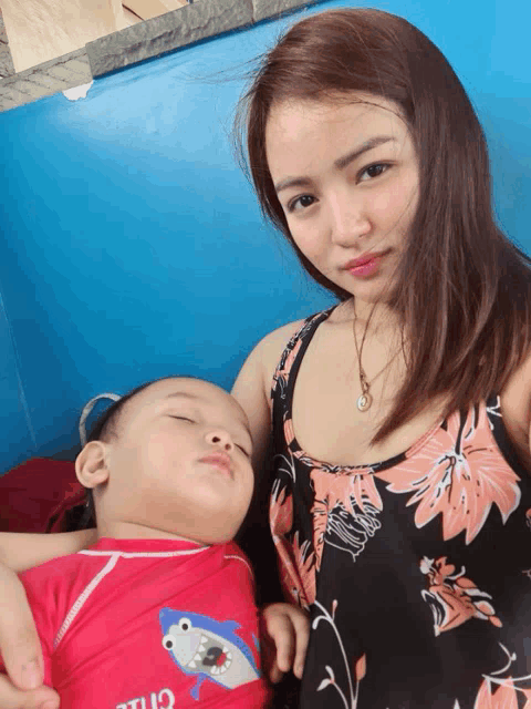 a woman holds a baby wearing a red shirt that says chill