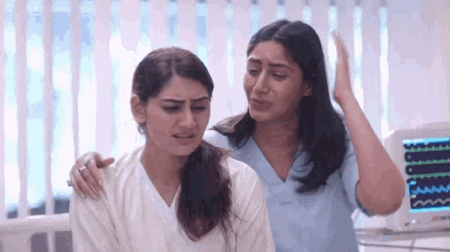 a nurse is comforting a woman in a hospital bed .