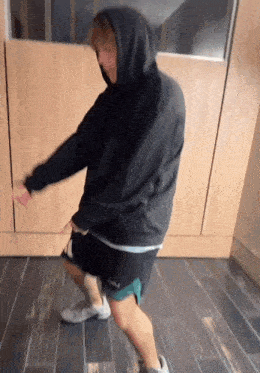 a man wearing a black hoodie and shorts is dancing