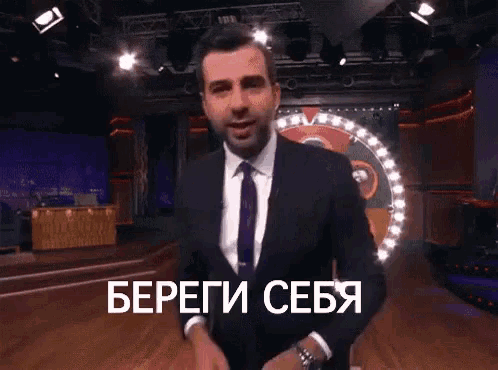 a man in a suit and tie is standing in front of a roulette wheel with russian writing on it .