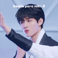 a young man in a suit and white shirt is giving a high five with the words besito para niki : 3 below him .