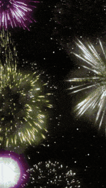a fireworks display with purple yellow and white fireworks in the night sky