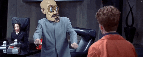 a man in a suit and goggles is talking to a man in a red jacket .