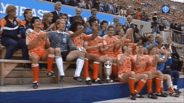 a group of soccer players are sitting on a bench with a trophy