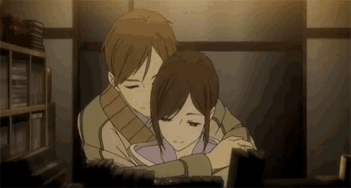 a man and a woman are hugging each other while looking at a computer screen .