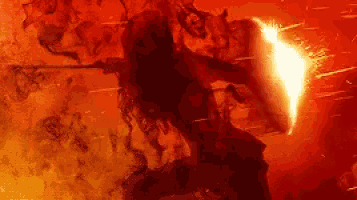 a man is holding a sword and shield in front of a fireball .