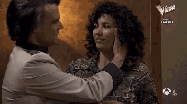 a man touches a woman 's face in front of a screen that says " voz "