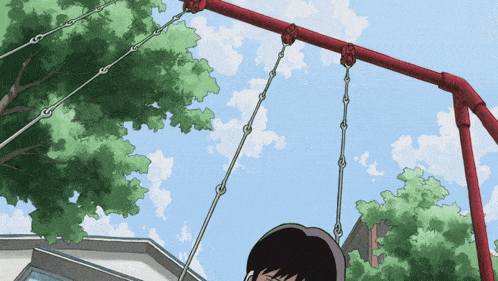 a boy is swinging on a red swing set in a park