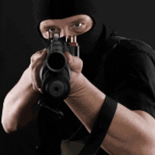 a man wearing a black mask is pointing a gun at the camera