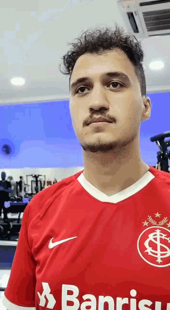 a man wearing a red banrisul jersey looks at the camera