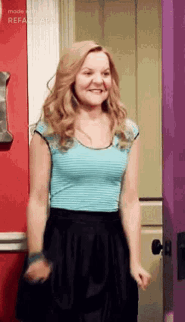 a woman wearing a blue striped shirt and a black skirt is standing in front of a purple door .