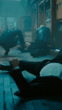 a man in a suit is laying on the floor with another man