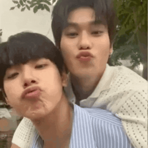 two young men are making funny faces for a picture while standing next to each other .